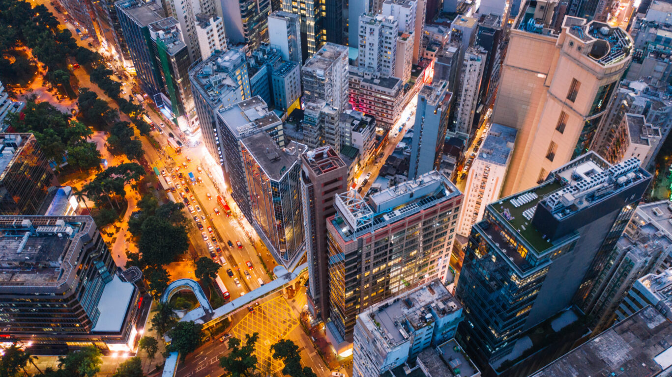 Aerial top view of downtown district buildings in night city light. Bird's eye view from drone of cityscape metropolis infrastructure, crossing streets with parked cars. Development infrastructure.