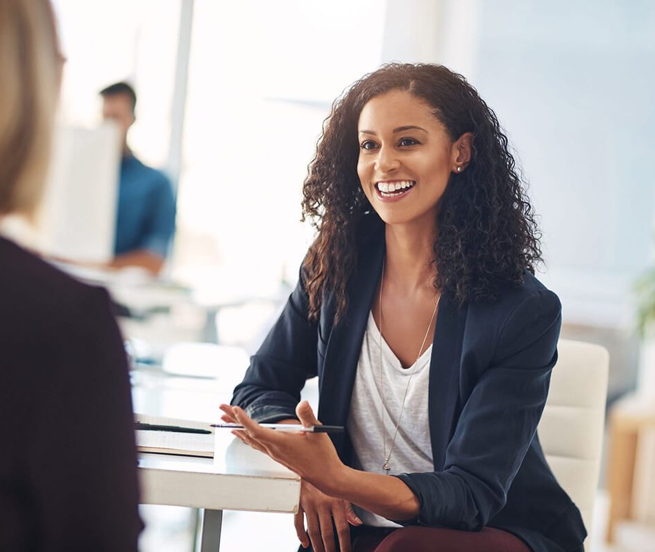 Quick catch up with a coworker. Shot of two young women having a conversation in a modern office.