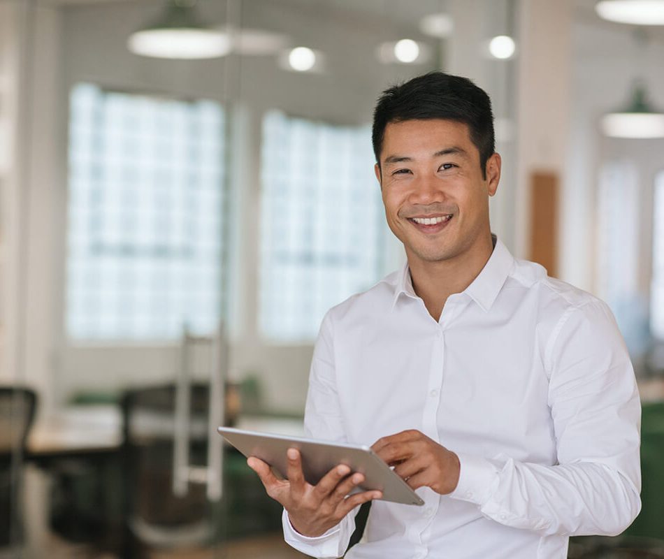 Smiling Asian businessman using a digital tablet in an office