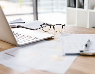 Desk with laptop, documents, and glasses symbolizing transfer pricing benchmarking analysis, compliance documentation, and financial reporting.