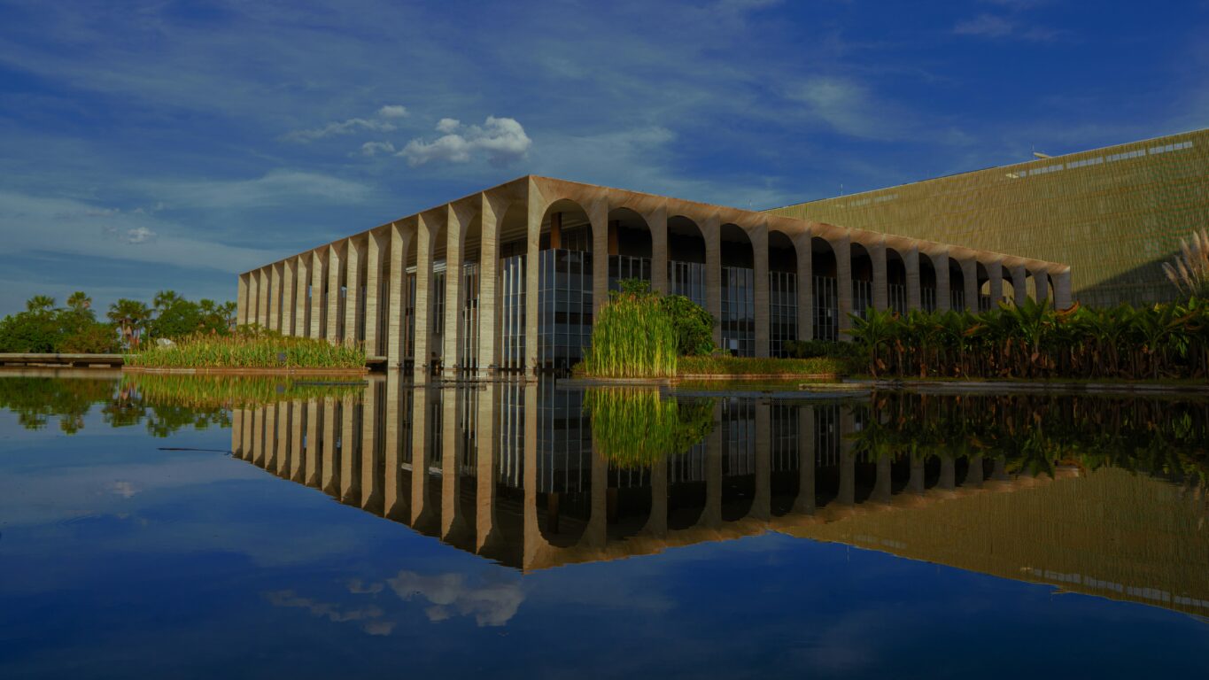The Palacio Itamaraty, also known as the Ministry of Foreign Affairs building in Brazil. The building sits surrounded by blue sky reflected in the bright blue water.