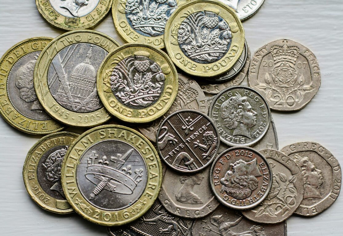 UK Currency: UK Sterling, one pound coins, five pence pieces, twenty pence pieces.