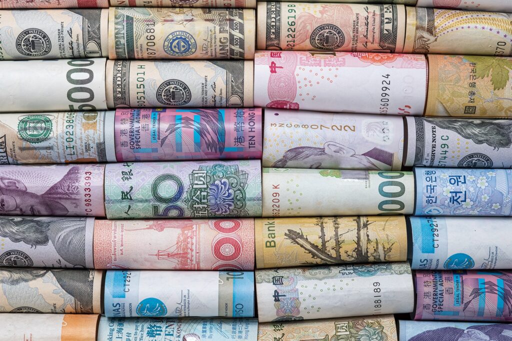 Rolled banknotes of various global currencies, including US dollars, euros, yen, won, and pesos, symbolizing international finance and intercompany transactions.